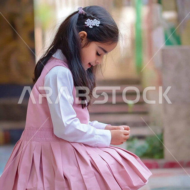 طالبة عربية خليجية سعودية ترتدي اليونيفورم المدرسي الخاص وتلعب في ساحة المدرسة بايماءات السعادة، الإستعداد للعام الدراسي الجديد، العوده إلى المدارس، تعابير الأدب والأخلاق، تنمية قدرات الأطفال الحركية والذهنية، المدارس الأكاديمية في المملكة العربية السعودية