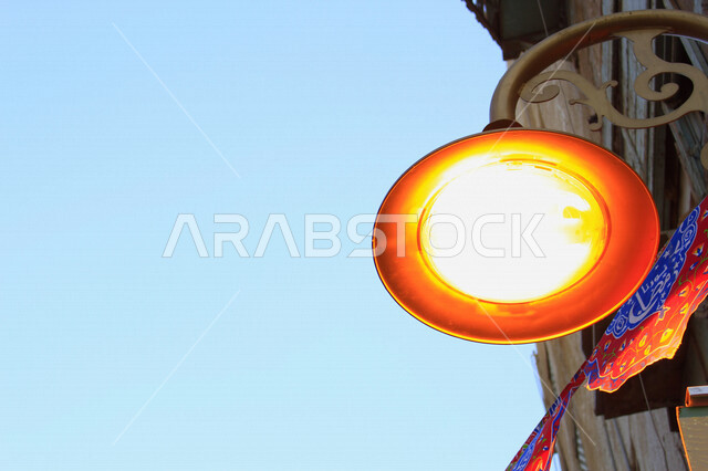 ضوء الشارع المعدني الأسود تحت السماء الزرقاء في المملكة العربية السعودية , منظر زاوية منخفضة للمصباح الكهربائي , ضوء الشارع معزول ضد خلفية السماء الزرقاء غائم في يوم صيف مشرق , عمود مصباح الشارع , الصورة المقربة , معالم تاريخية أثرية