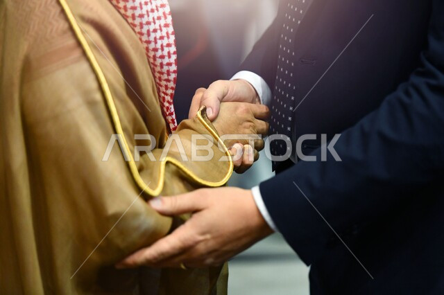  عقد اتفاقات العمل في الامارات العربية المتحدة، مفهوم الصفح والتسامح, إلقاء السلام والتحية,صورة مقربة ليدي رجلين عربيين اماراتيين خليجيين يتصافحان سوياً, بناء العلاقات الاجتماعية المتينة في المجتمع الاماراتي