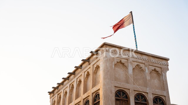 أعلام الدول العربية, صورة مقربة لعلم دولة قطر فوق المعالم الأثرية المشهورةمعلق يرفرف في السماء, الرموز الوطنية القطرية، اليوم الوطني القطري, مفهوم حب الوطن والانتماء اليه