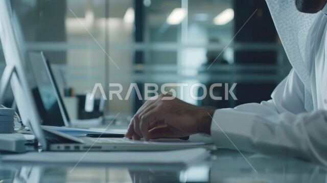 مفهوم إدارة شؤون الأعمال وتنظيمها عبر الاجهزة التقنية، دمج العمل مع التقنية والتكنولوجيا، صورة مقربة ليدي رجل عربي خليجي سعودي يقوم بالعمل على جهاز الحاسوب المحمول داخل المكتب، مهن ووظائف ادارية مكتبية في المملكة العربية السعودية