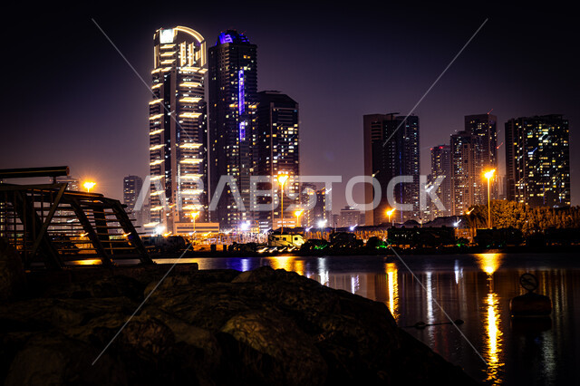 Attractions and tourist attractions, the reflection of lights and lights of hotels and buildings on the sea water at night, the architectural art of building towers and skyscrapers on Al Mamzar Beach, the coastal waterfront in Dubai, urban growth and development in the United Arab Emirates