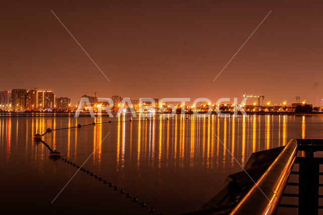 Architectural engineering art in building towers and skyscrapers on Al Mamzar Beach, the coastal waterfront in Dubai, the reflection of lights and lights of hotels and buildings on the sea water at night, urban growth and development in the United Arab Emirates, tourist attractions and attractions