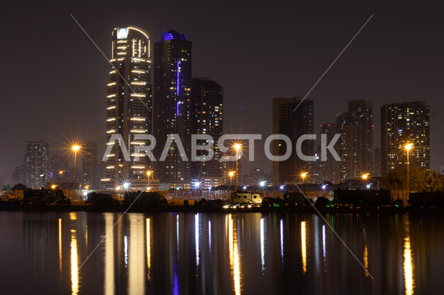 الفن الهندسي المعماري في بناء الأبراج وناطحات السحاب على شاطئ الممزر, الواجهة البحرية الساحلية في مدينة دبي, انعكاس الأضواء والأنوار للفنادق والمباني على مياه البحر في وقت الليل، النمو والتطور العمراني في الامارات العربية المتحدة, وجهات جذب واستقطاب السياح