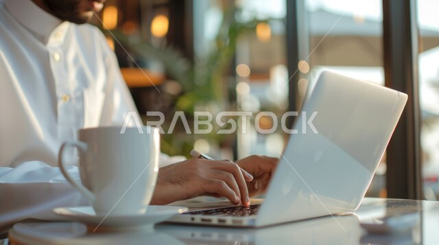 مفهوم إدارة شؤون الأعمال وتنظيمها عبر الاجهزة التقنية، دمج العمل مع التقنية والتكنولوجيا، صورة مقربة ليدي رجل عربي خليجي سعودي يقوم بالعمل على جهاز الحاسوب المحمول داخل المكتب، مهن ووظائف ادارية مكتبية في المملكة العربية السعودية