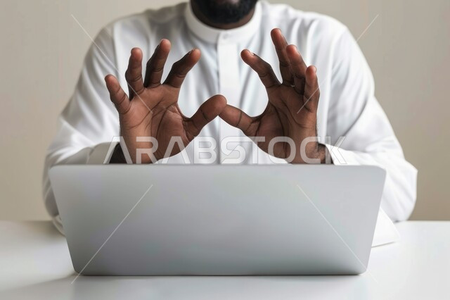 مفهوم إدارة شؤون الأعمال وتنظيمها عبر الاجهزة التقنية، دمج العمل مع التقنية والتكنولوجيا، صورة مقربة ليدي رجل عربي خليجي سعودي يقوم بالعمل على جهاز الحاسوب المحمول داخل المكتب، مهن ووظائف ادارية مكتبية في المملكة العربية السعودية