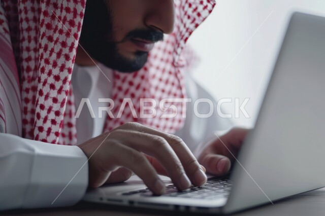 مفهوم إدارة شؤون الأعمال وتنظيمها عبر الاجهزة التقنية، دمج العمل مع التقنية والتكنولوجيا، صورة مقربة ليدي رجل عربي خليجي سعودي يقوم بالعمل على جهاز الحاسوب المحمول داخل المكتب، مهن ووظائف ادارية مكتبية في المملكة العربية السعودية