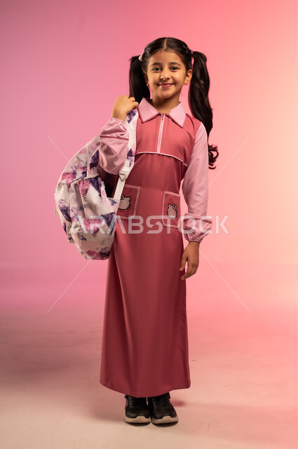 Education in Saudi Arabia, preparing for the new school year, joy of returning to school, portrait of a Saudi Arabian Gulf girl wearing a school uniform carrying a school bag on her back looking at the camera with gestures of happiness and pleasure, full body, colorful background