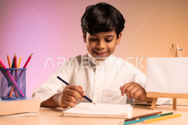مراجعة الدروس بجد واجتهاد للوصول إلى النجاح والتفوق، إيماءات الاندماج والتركيز في حل وكتابة الواجبات، العودة إلى المدارس، بورتريه لطالب عربي خليجي سعودي يرتدي الثوب التقليدي يجلس في مقعده، قرطاسية مدسية ولوحة بيضاء فارغة على الطاولة المكتبية، خلفية ملونة