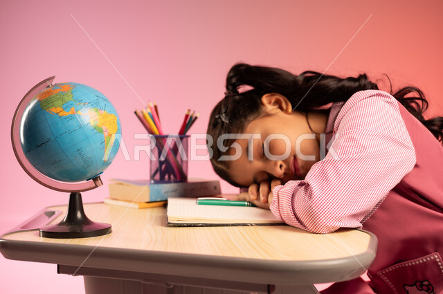 Fatigue and need for rest and sleep, school stationery and globe on desk, education in Saudi Arabia schools, back to school season, side portrait of a Saudi Arabian Gulf Arab female student wearing official school uniform sitting in her seat and taking a nap, colorful background