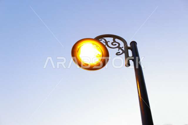 ضوء الشارع المعدني الأسود تحت السماء الزرقاء في المملكة العربية السعودية , منظر زاوية منخفضة للمصباح الكهربائي , ضوء الشارع منير , عمود مصباح الشارع , الصورة المقربة , معالم تاريخية أثرية