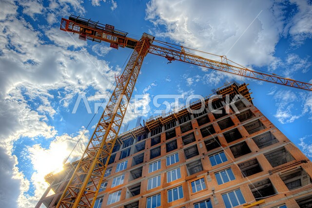 Construction works, concrete pouring and foundation laying, heavy machinery and equipment, cranes and high scaffolding, building under construction in Saudi Arabia, concept of structural and architectural engineering, implementation of construction plan and formation of metal structure