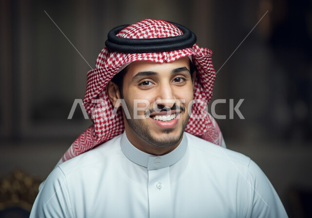 الاهتمام بالأناقة والمظهر الخارجي، الصور الشخصية للوثائق الرسمية، مفهوم الرجولة والثقة بالنفس، بورتريه مقرب لرجل عربي خليجي سعودي ذو شعر قصير داكن ولحية مشذبة يرتدي الشماغ والزي التقليدي ينظر الى الكاميرا بتعابير السرور