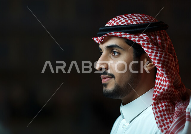 Concern for elegance and appearance, personal photos for official documents, concept of masculinity and self-confidence, close-up side portrait of a Saudi Arabian Gulf man with short dark hair and trimmed beard wearing a shemagh and traditional dress