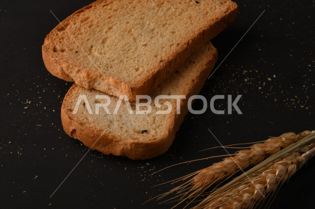 مجموعة من نباتات القمح ، شرائح خبز التوست المحمصة على خلفية سوداء