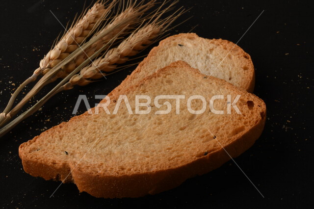 مجموعة من نباتات القمح ، شرائح خبز التوست المحمصة على خلفية سوداء