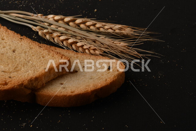 مجموعة من نباتات القمح ، شرائح خبز التوست المحمصة على خلفية سوداء