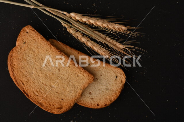 مجموعة من نباتات القمح ، شرائح خبز التوست المحمصة على خلفية سوداء