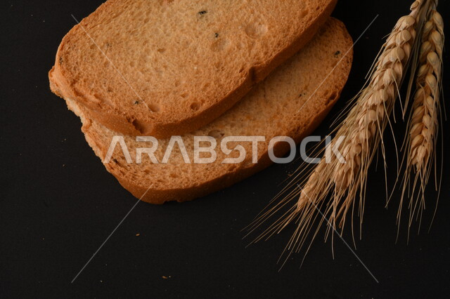 مجموعة من نباتات القمح ، شرائح خبز التوست المحمصة على خلفية سوداء