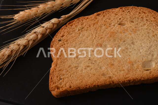 مجموعة من نباتات القمح ، شرائح خبز التوست المحمصة على خلفية سوداء