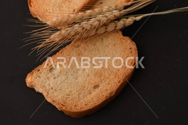 مجموعة من نباتات القمح ، شرائح خبز التوست المحمصة على خلفية سوداء