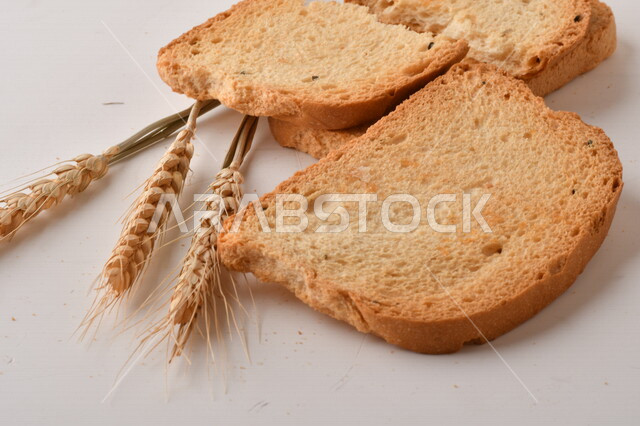 مجموعة من نباتات القمح ، صورة مقربة لشرائح خبز التوست المحمصة على خلفية بيضاء