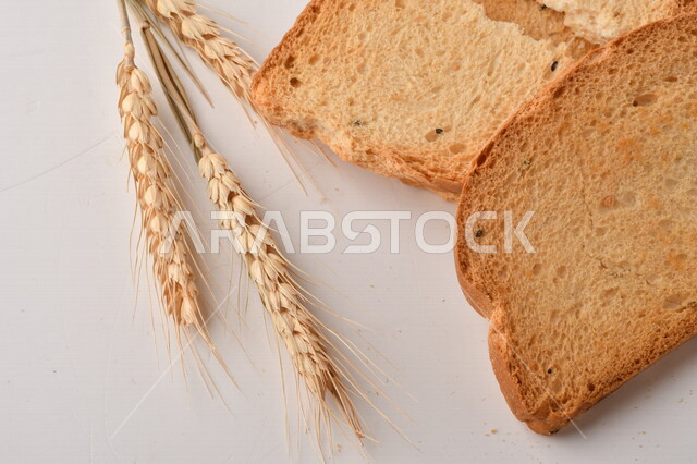 مجموعة من نباتات القمح ، صورة مقربة لشرائح خبز التوست المحمصة على خلفية بيضاء