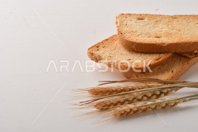 مجموعة من نباتات القمح ، صورة مقربة لشرائح خبز التوست المحمصة على خلفية بيضاء