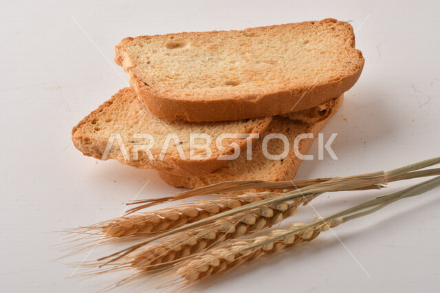 مجموعة من نباتات القمح ، صورة مقربة لشرائح خبز التوست المحمصة على خلفية بيضاء