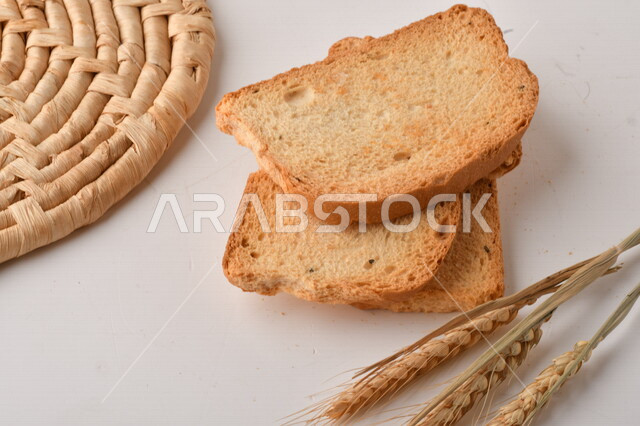 مجموعة من نباتات القمح ، صورة مقربة لشرائح خبز التوست المحمصة على خلفية بيضاء