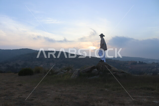 صورة من الخلف لرجل يقف على قمة جبل يتأمل منظر غروب الشمس, المرتفعات الجبلية وزراعة النباتات الخضراء,خلفية الطبيعة