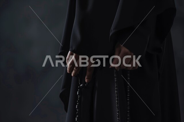 التهليل والتسبيح وذكر الله تعالى، بورتريه مقرب لأيدي إمرأة عربية خليجية سعودية تمسك بيدها السبحة تقوم بالاستغفار، قراءة الأدعية والأذكار، المناسبات الدينية والإسلامية، مفهوم العبادة والتقرب لرب العالمين، خلفية رمادية