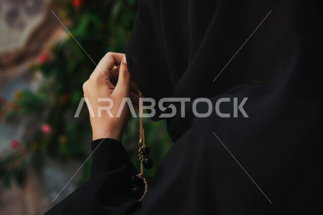 التهليل والتسبيح وذكر الله تعالى، بورتريه مقرب لأيدي إمرأة عربية خليجية سعودية تمسك بيدها السبحة تقوم بالاستغفار، قراءة الأدعية والأذكار، المناسبات الدينية والإسلامية، مفهوم العبادة والتقرب لرب العالمين، خلفية رمادية