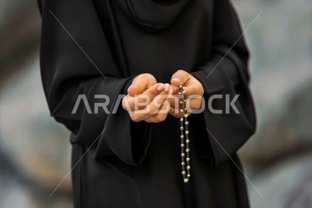 التهليل والتسبيح وذكر الله تعالى، بورتريه مقرب لأيدي إمرأة عربية خليجية سعودية تمسك بيدها السبحة تقوم بالاستغفار، قراءة الأدعية والأذكار، المناسبات الدينية والإسلامية، مفهوم العبادة والتقرب لرب العالمين، خلفية رمادية