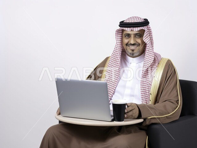 مهن ووظائف ادارية مكتبية، دمج العمل مع التقنية والتكنولوجيا، إدارة شؤون الأعمال وتنظيمها عبر الاجهزة التقنية، بورتريه لرجل اعمال عربي خليجي سعودي يرتدي الشماغ والثوب التقليدي عمل على الحاسوب المحمول داخل المكتب، الاستمتاع بمشروب القهوة الساخن، خلفية بيضاء