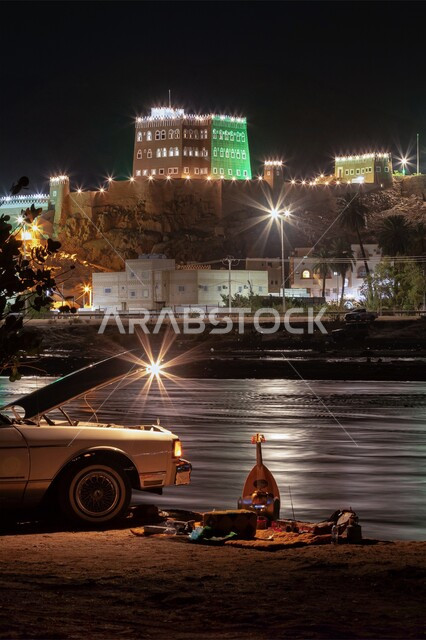 A simple popular session in front of the lake in the open air at night, enjoying the tranquility and sitting in front of Al-Aan Palace in the city of Najran, tourist places in Hail Governorate in the Kingdom of Saudi Arabia