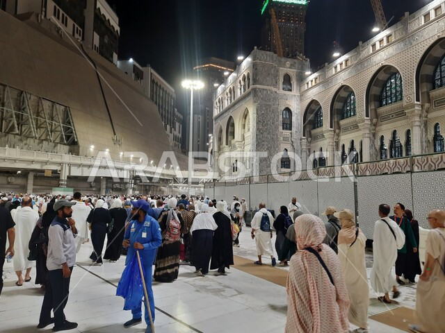 مبنى برج الساعة الملكي في المسجد الحرام المضيء ليلا، الحجاج والمعتمرين في الحرم المكي الشريف، الفن الهندسي المعماري على الطراز الإسلامي للابراج وناطحات السحاب في مكة المكرمة، معالم وأماكن دينية مقدسة في المملكة العربية السعودية