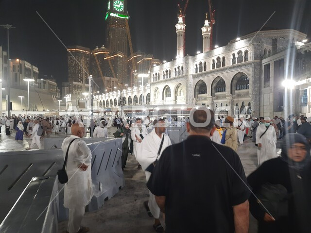 مبنى برج الساعة الملكي في المسجد الحرام المضيء ليلا، الحجاج والمعتمرين في الحرم المكي الشريف، الفن الهندسي المعماري على الطراز الإسلامي للابراج وناطحات السحاب في مكة المكرمة، معالم وأماكن دينية مقدسة في المملكة العربية السعودية