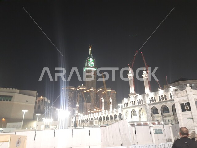 مبنى برج الساعة الملكي في المسجد الحرام المضيء ليلا، الحجاج والمعتمرين في الحرم المكي الشريف، الفن الهندسي المعماري على الطراز الإسلامي للابراج وناطحات السحاب في مكة المكرمة، معالم وأماكن دينية مقدسة في المملكة العربية السعودية
