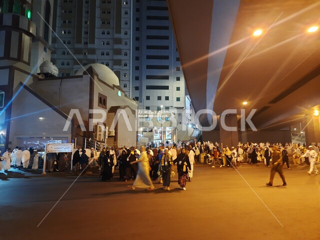 Visitors to the House of God gather in the outer courtyard of the Grand Mosque, Muslims from all over the world come to the holy religious places, famous Islamic landmarks in the Kingdom of Saudi Arabia, streets and roads of Mecca illuminated at night