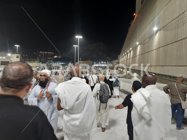 آداء مناسك الحج والعمرة، المعالم الاسلامية المشهورة في المملكة العربية السعودية، قدوم المسلمين من جميع أنحاء العالم إلى الاماكن الدينية المقدسة, تجمع زوار بيت الله الحرام في الفناء الخارجي للمسجد الحرام المضيء ليلا في مكة المكرمة