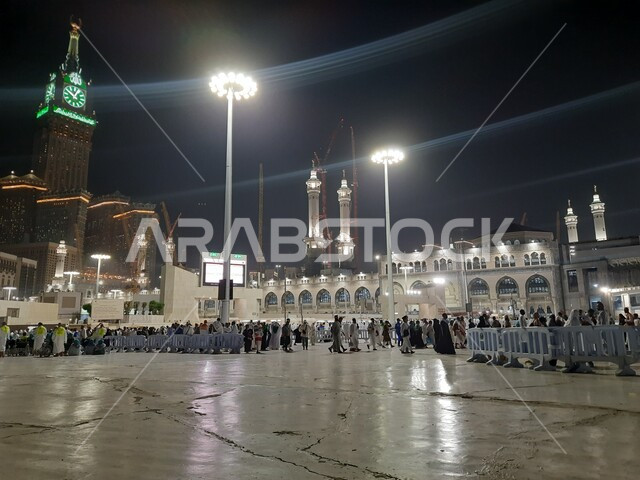 مبنى برج الساعة الملكي المضيء ليلا، قدوم المسلمين من جميع أنحاء العالم إلى الاماكن الدينية المقدسة,المعالم الاسلامية المشهورة في المملكة العربية السعودية، تجمع زوار بيت الله في الفناء الخارجي للمسجد الحرام في مكة المكرمة