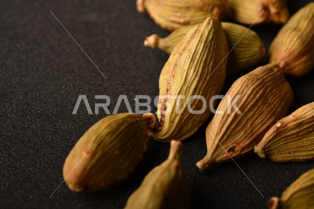 حب الهال (حبهان) المجفف على خلفية طاولة رمادية , الهيل الأخضر (إليشي) ذات الرائحة والنكهة العطرية , صورة مقربة لحب الهال الأخضر