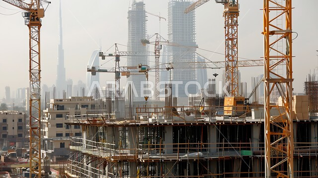 موقع بناء مزدحم بالآلات والمعدات الثقيلة والرافعات والسقالات العالية, اعمال البناء وصب الخرسانات ووضع الأساسات، مبنى قيد الانشاء في المملكة العربية السعودية, مفهوم الهندسة الانشائية والمعمارية، تنفيذ مخطط الإعمار وتشكيل الهيكل المعدني