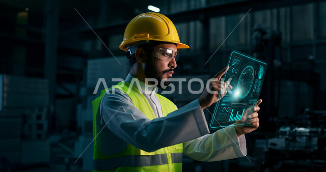 الاستفادة من التقنيات الحديثة والتكنولوجيا المتطورة في مجال الهندسة، مهندس عربي خليجي سعودي يرتدي خوذة الحماية وسترة الوقاية يقوم بالنقر على أيقونات هولوجرامية تظهر في شاشة على شكل تابلت، متابعة الأعمال والإشراف عليها عن قرب، مهن ووظائف سعودية