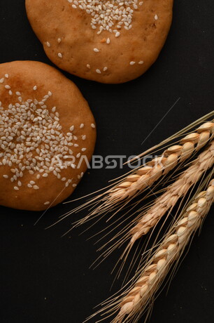 صورة مقربة لمجموعة من نباتات القمح ، وبسكويت القمح الهشة والمقرمشة على خلفية سوداء