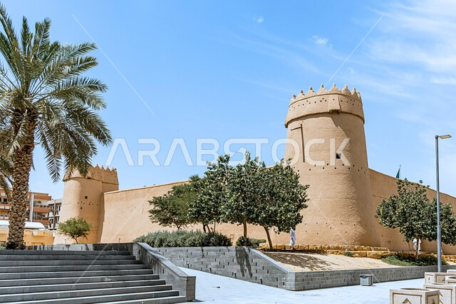 فن الهندسة المعمارية والمباني الطينية القديمة، أشجار النخيل حول متحف قصر المصمك التاريخي في مدينة الرياض في وضح النهار، الاهتمام بالتشجير والنباتات الخضراء في الاماكن الاثرية السياحية في المملكة العربية السعودية، معالم الرياض التراثية