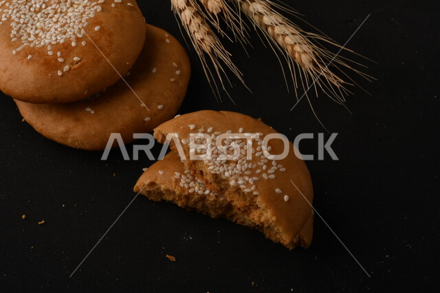 صورة مقربة لمجموعة من نباتات القمح ، وبسكويت القمح الهشة والمقرمشة على خلفية سوداء