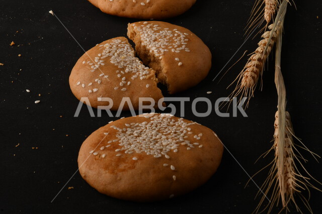 صورة مقربة لمجموعة من نباتات القمح ، وبسكويت القمح الهشة والمقرمشة على خلفية سوداء