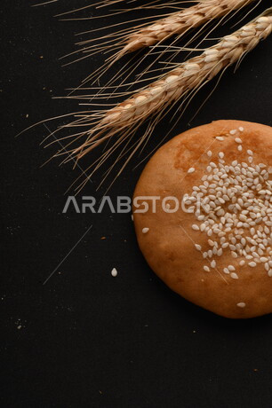 صورة مقربة لمجموعة من نباتات القمح ، وبسكويت القمح الهشة والمقرمشة على خلفية سوداء